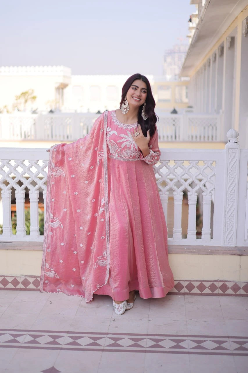 Woman in a pink traditional outfit standing on a balcony with white railings.